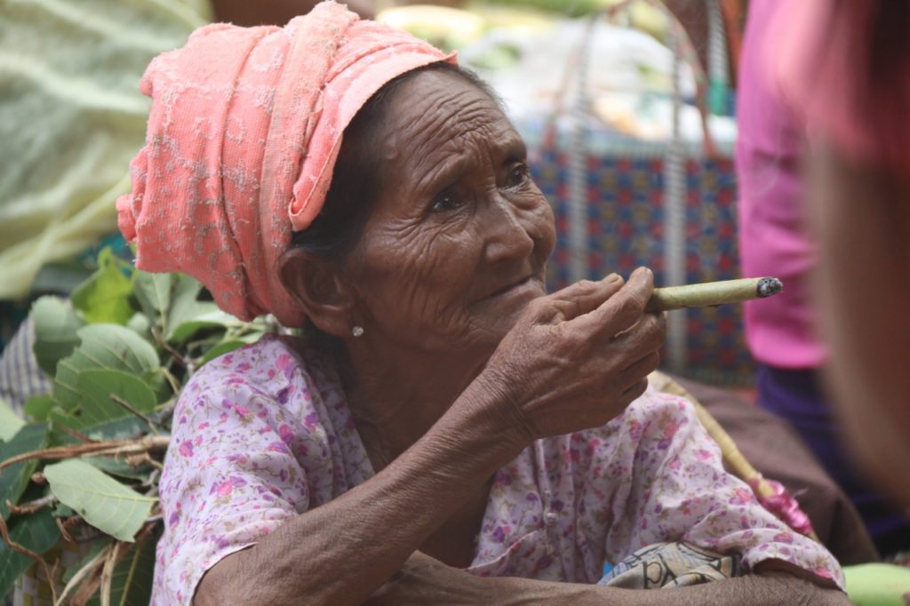 A LADY SMOKING A CIGAR AT BAGAN MARKET