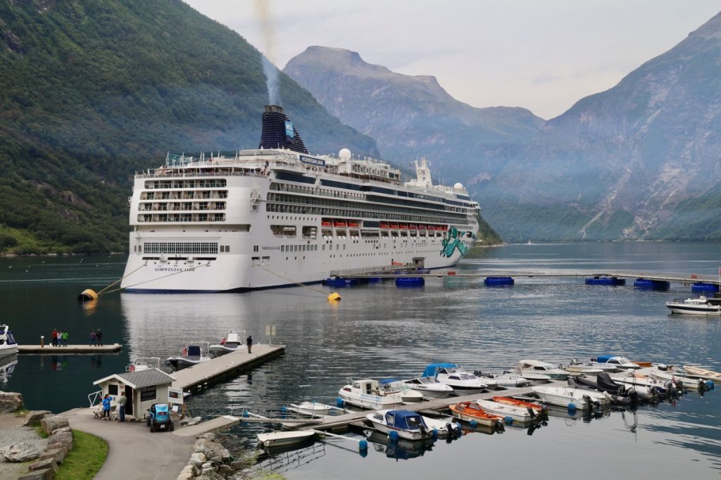 A cruise boat docked in front of the Geiranger Hotel